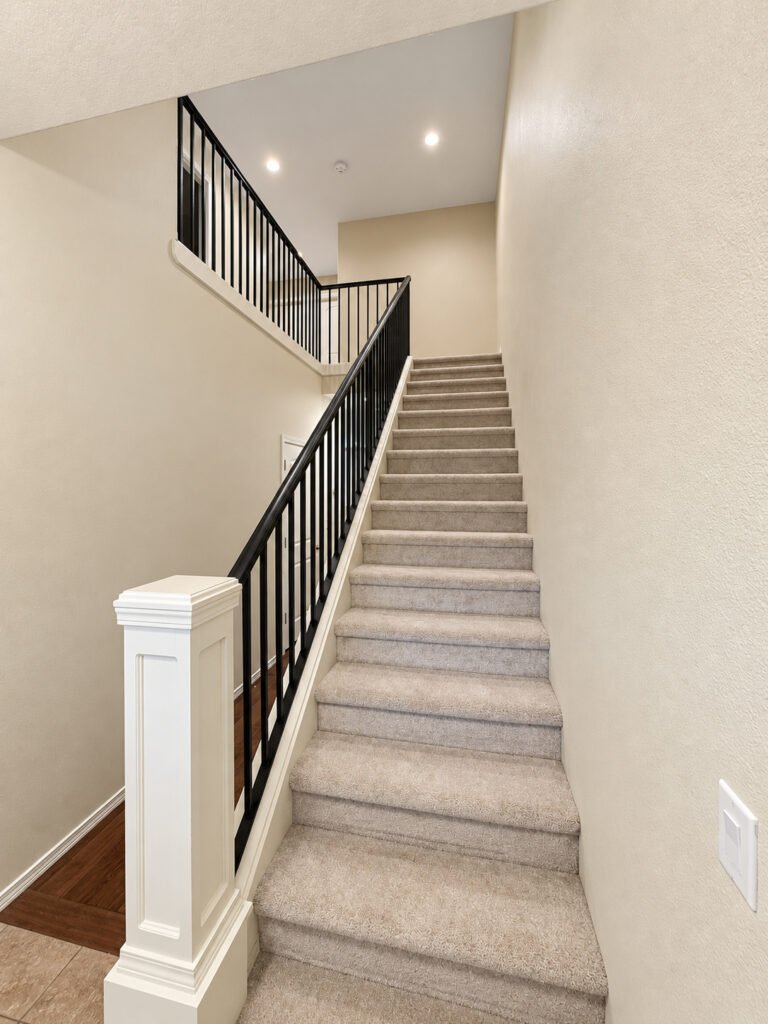 Staircase with carpeted steps and iron railing