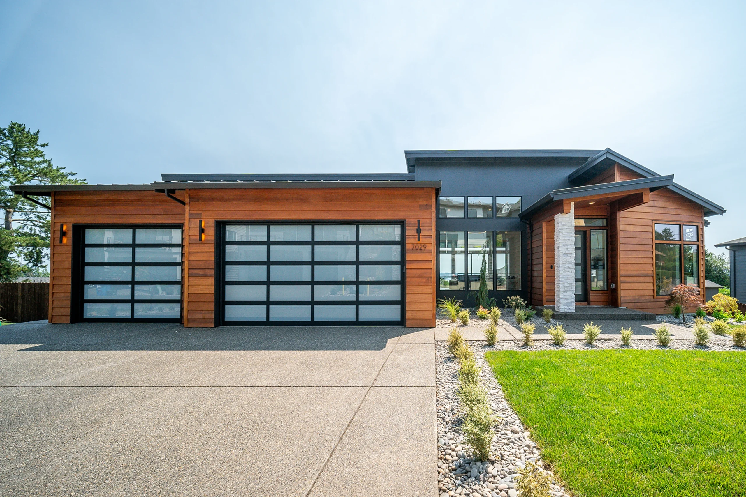 Cedar and stone modern home with glass garage doors, built by KHR Homes